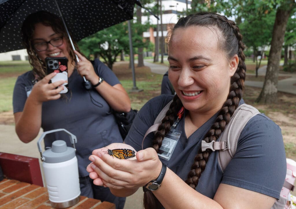 UA Little Rock nursing student Louise Hobby (right) releases a monarch butterfly while her classmate, Jennifer Camacho (left), records the interaction. Photo by Ben Krain.
