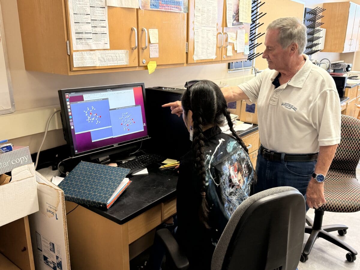 Two individuals work at a computer.