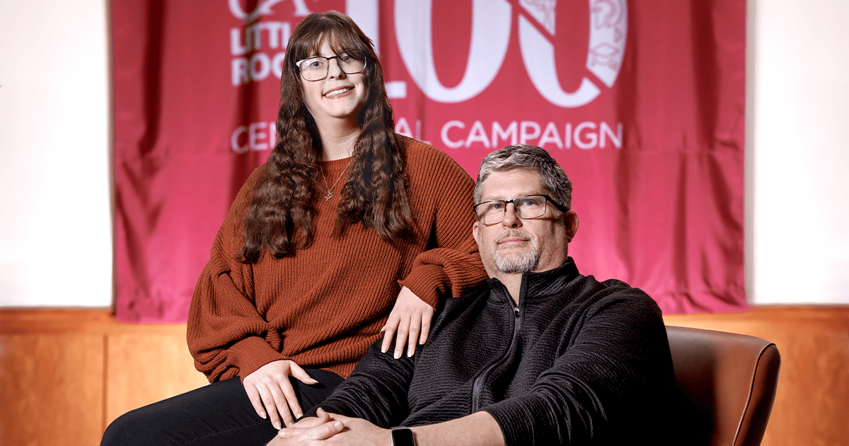 Robert and Madison Birch pose for a photo in front of a maroon UA Little Rock Centennial Campaign banner.