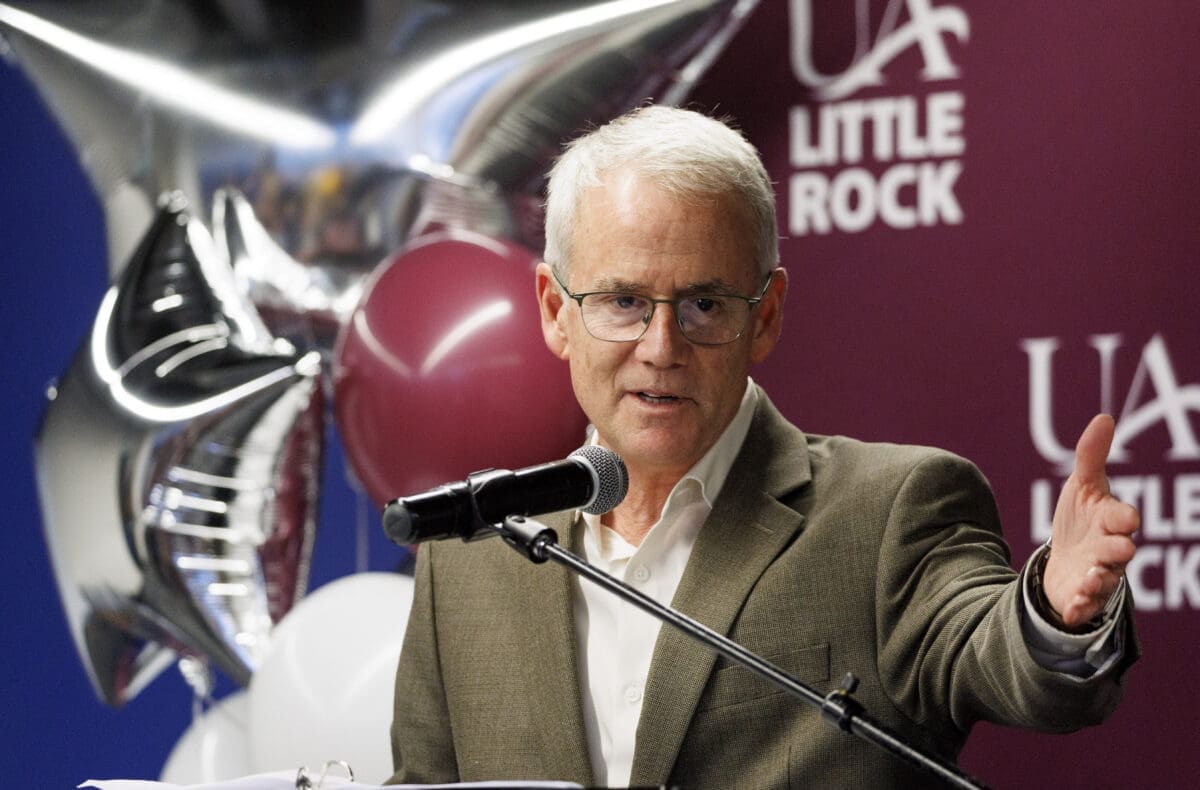 University of Arkansas System President Jay Silveria speaks to an audience, as balloons drape against a maroon UA Little Rock backdrop.
