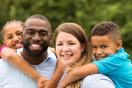 Photo of a smiling family in the park.