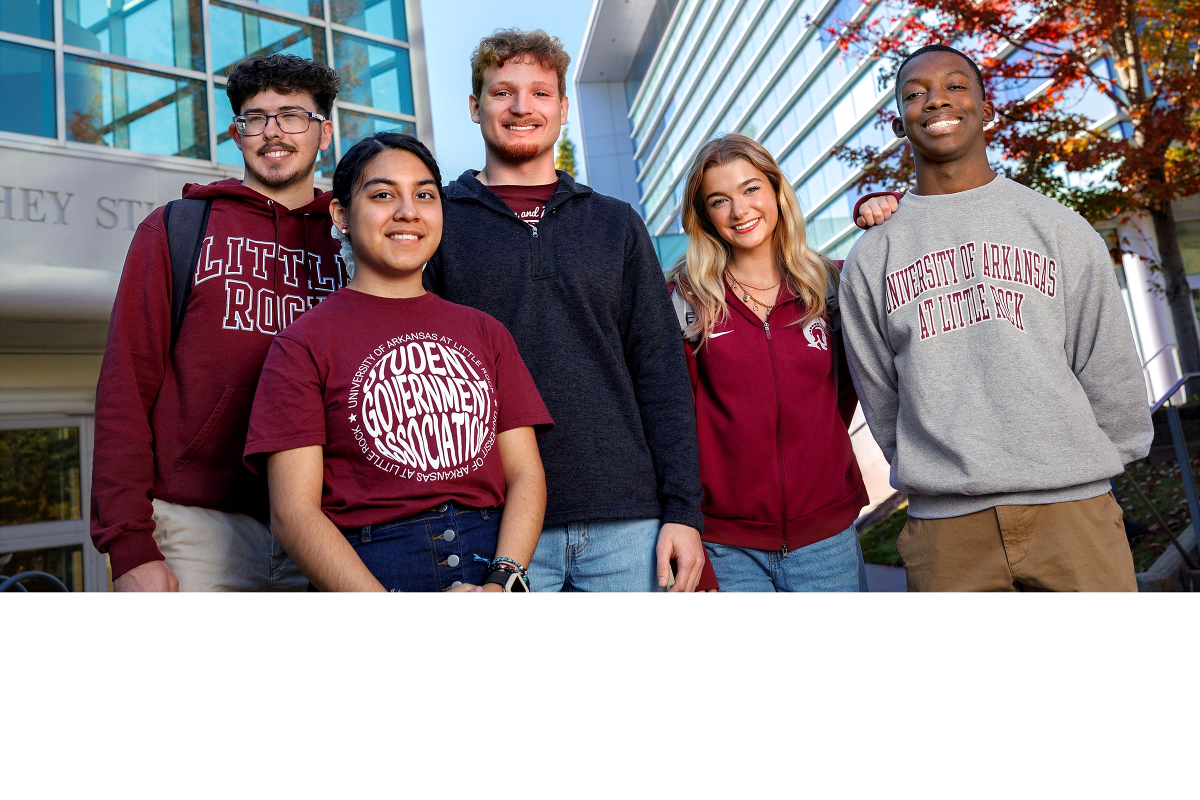 Five students standing outside in front of buildings on campus.