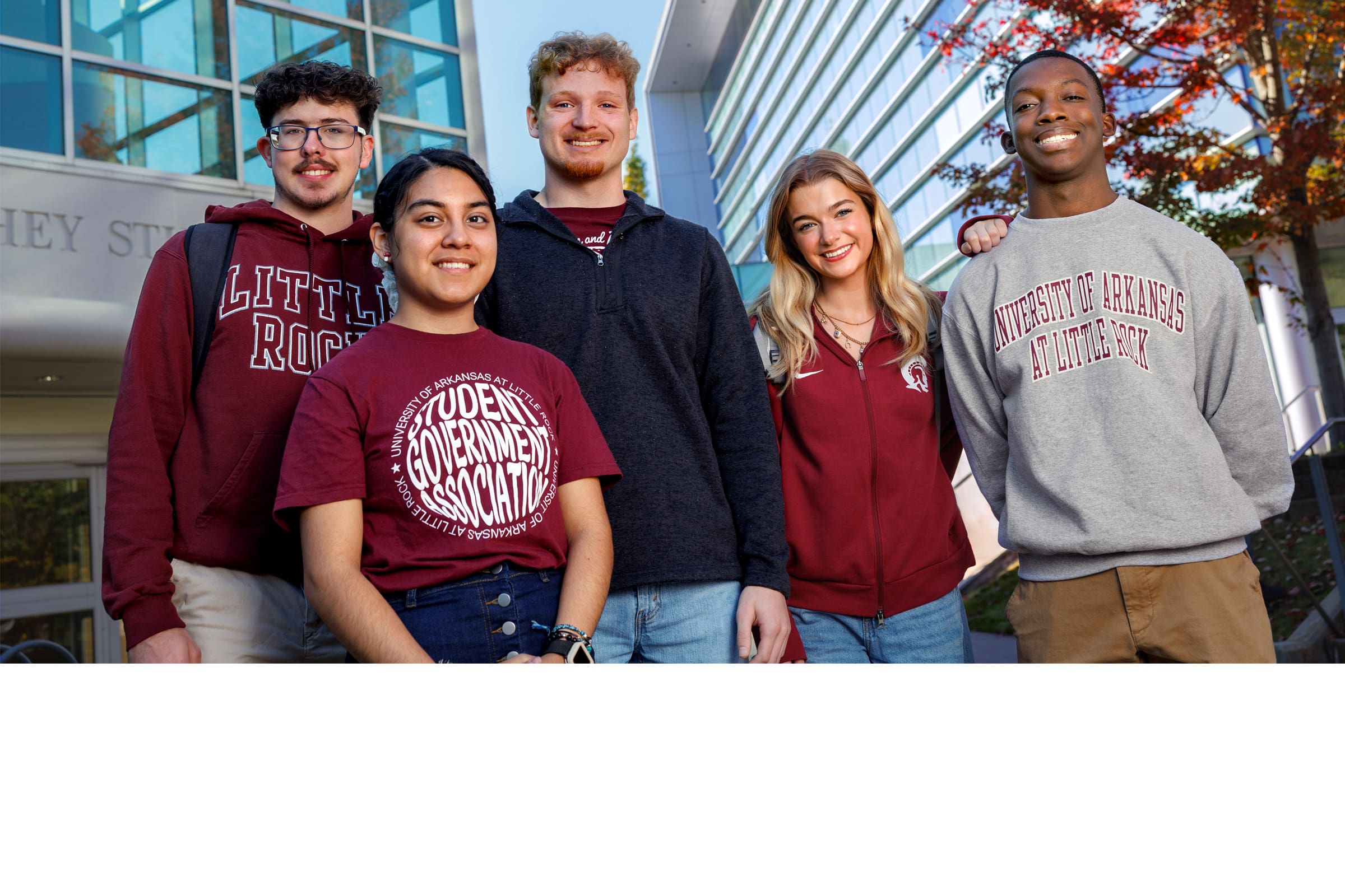 Five students standing outside in front of buildings on campus.